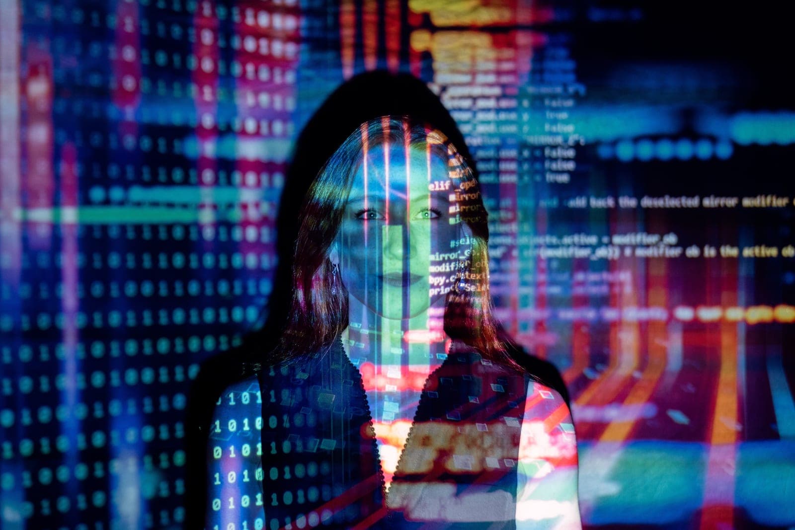 A woman standing in an office in front of a screen of code snippets